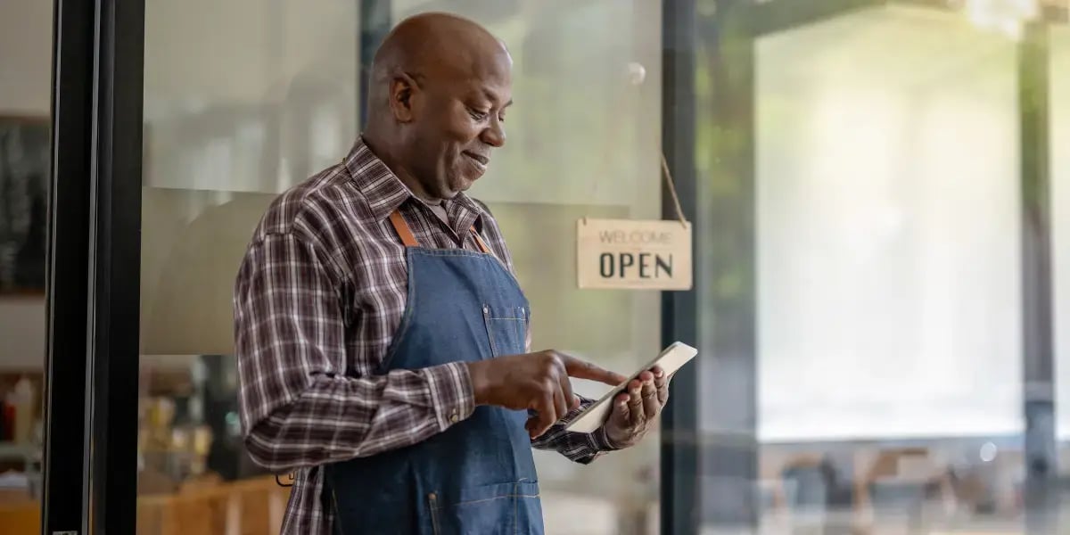 New business owner on his phone standing outside of his business front