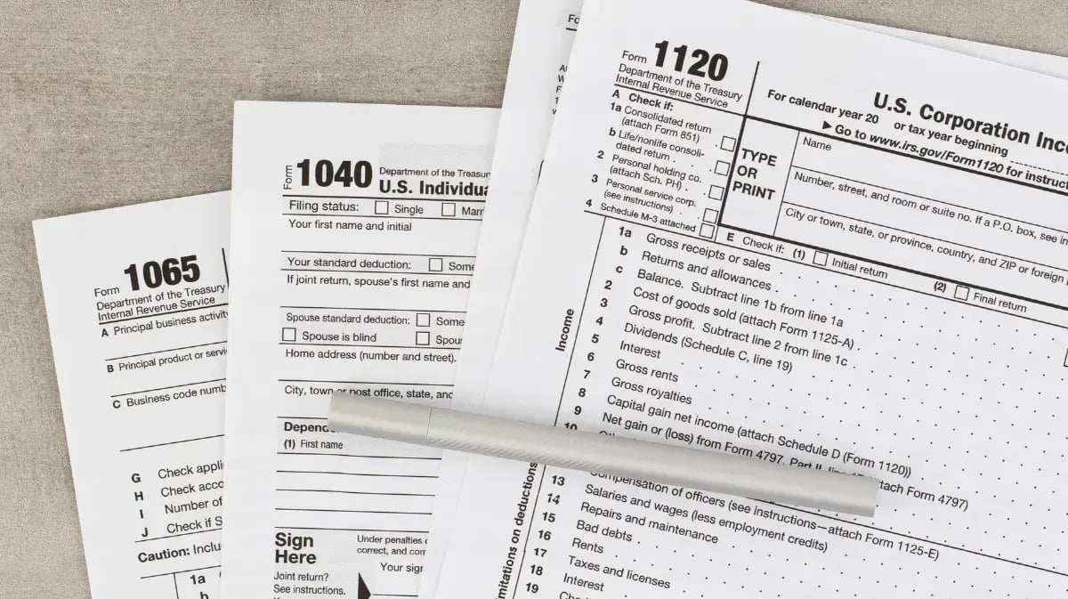 forms 1065, 1040, and 1120 on a desk