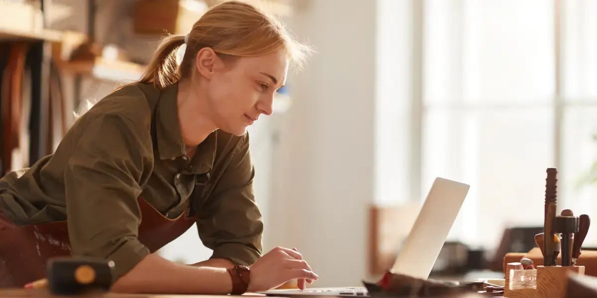 Business owner leaning a table working on her laptop