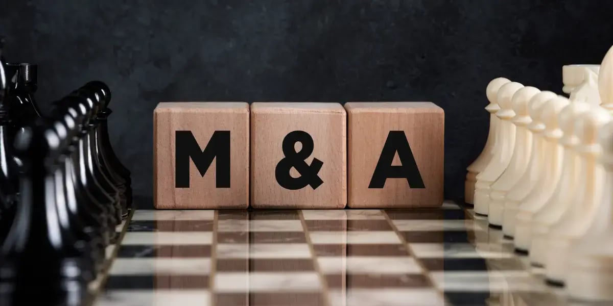 M&A on wooden blocks sitting on a chess board