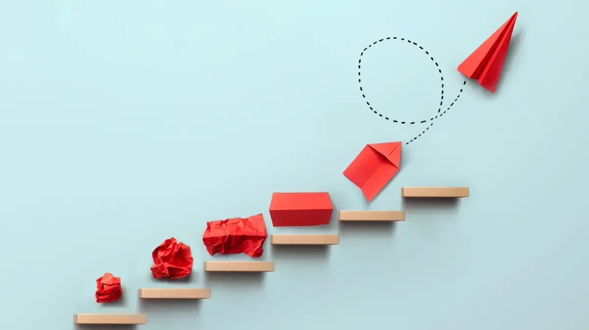 steps with crumbled paper on them that transform into a paper plane
