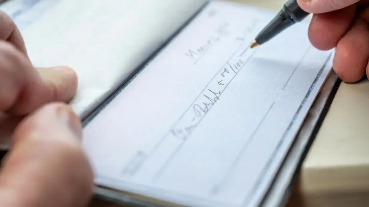 person writing information on a paper check
