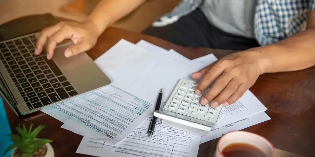 Small business owners reviewing tax forms with a laptop and calculator.