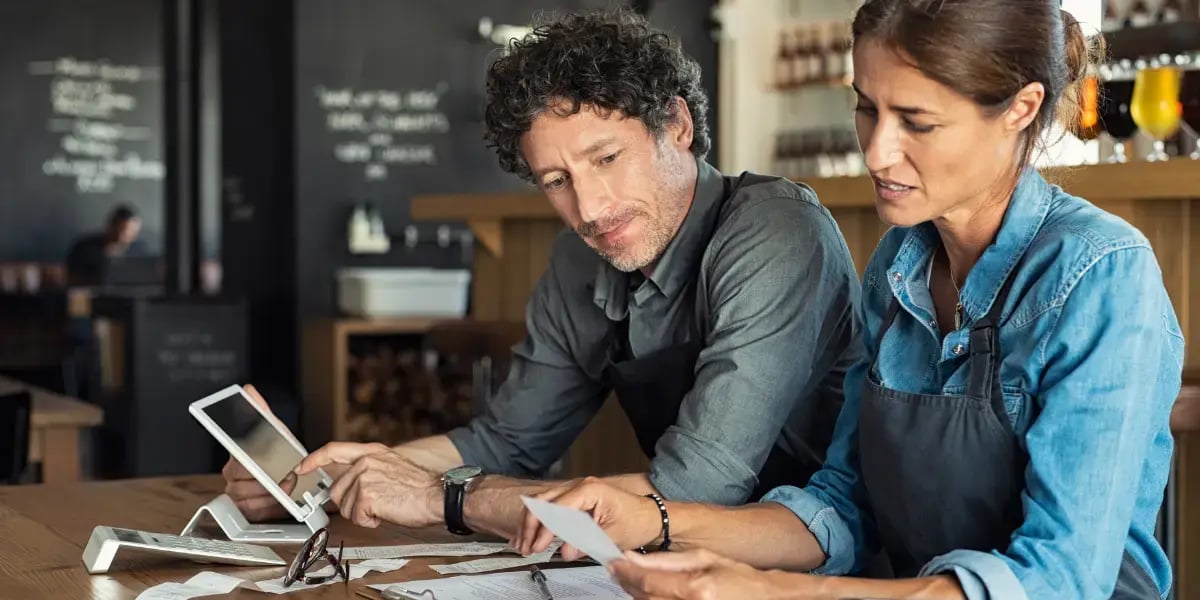 Two business owners working on their bookkeeping at a table in their store