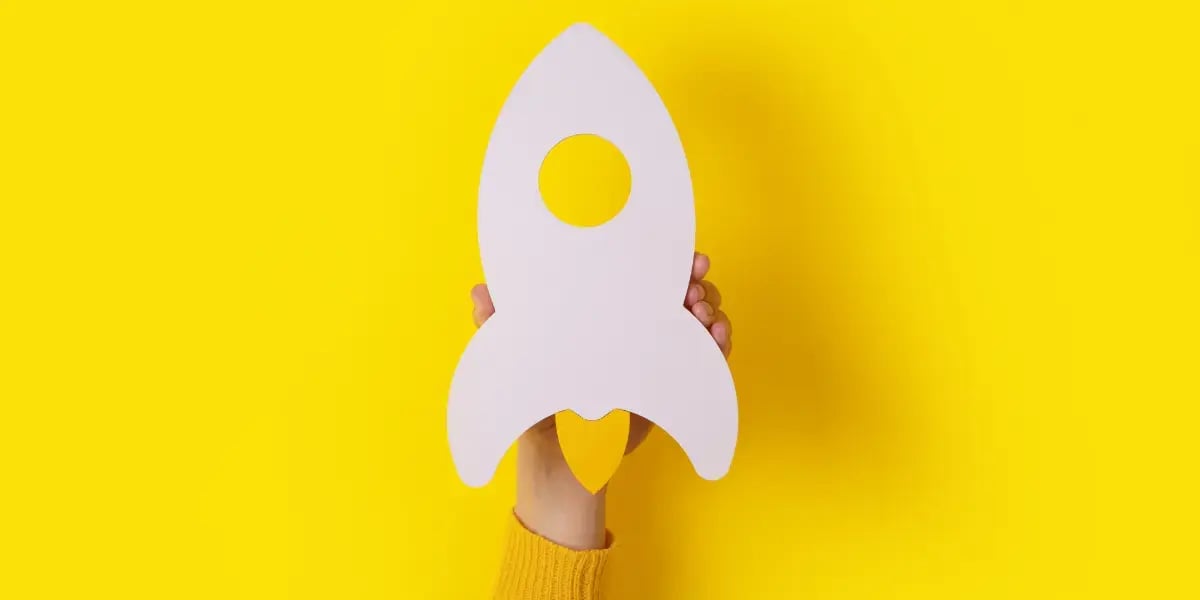 yellow backdrop with a rocket ship representing a startup business in the foreground