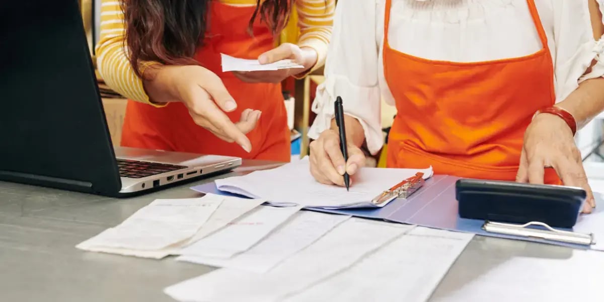 Business owners doing their bookkeeping on a desk with papers and receipts spread out across a table